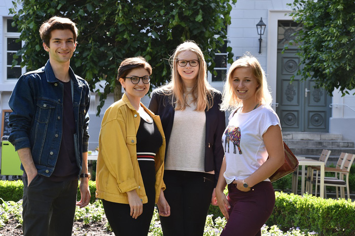 Drei junge Personen, die in die Kamera lächeln